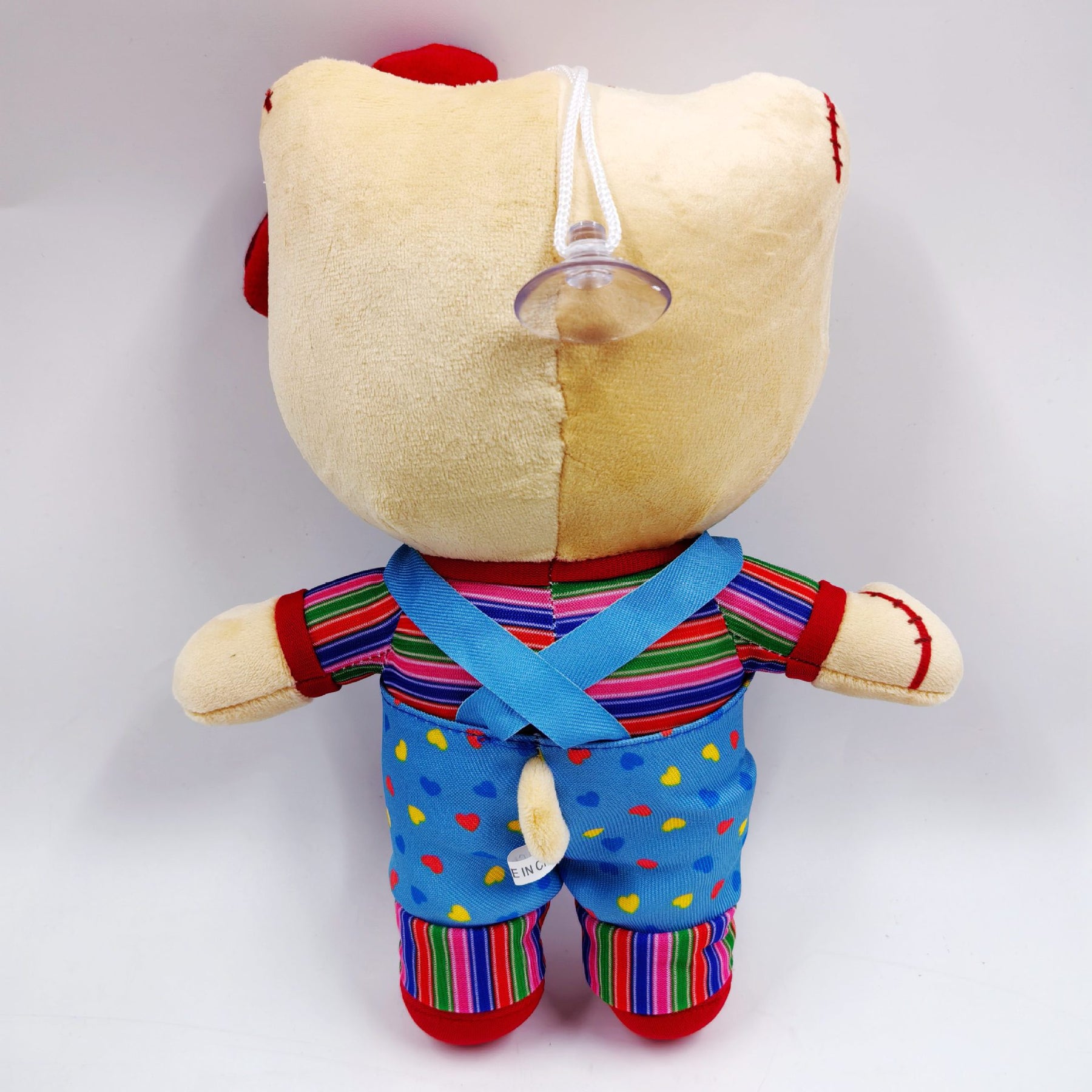 Personagem Hello Kitty com cicatrizes no rosto, laço remendado e macacão azul sobre camiseta listrada