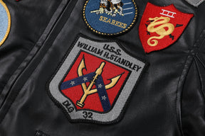 Jaqueta bomber preta com gola de pelo marrom e diversos patches militares no peito, costas e mangas