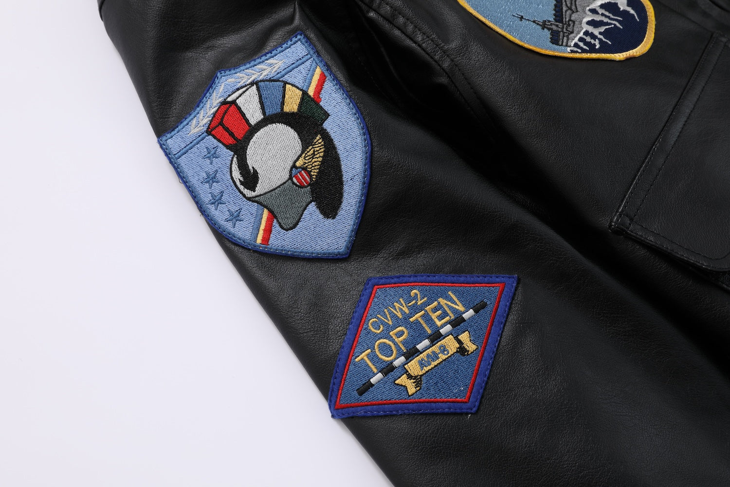 Jaqueta bomber preta com gola de pelo marrom e diversos patches militares no peito, costas e mangas