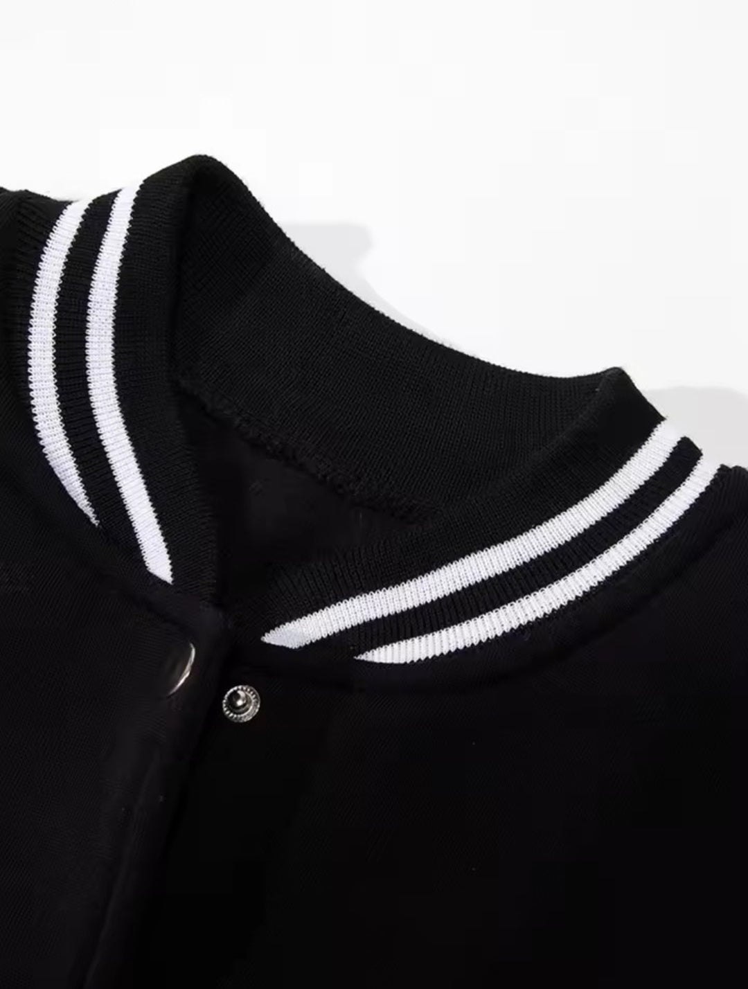 Jaqueta college bicolor preta e branca com estampas Los Angeles, California e fechamento por botões de pressão